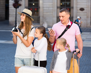 parents with two kids using smartphone and photographing sights during their travel