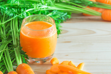 Fresh carrot juice in glass on wooden table with copy space