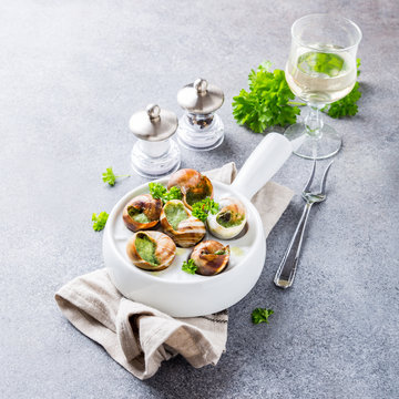 Bourgogne Escargot Snails with garlic herbs butter in white pan on light gray background. Healthy food concept with copy space.