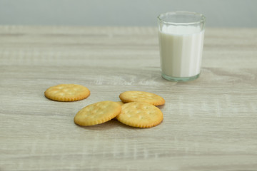 MILK GLASS AND CRACKERS
A glass of milk with pile of crackers on the wood top table. 