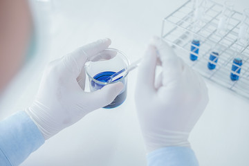 Medical or scientific researcher or man doctor looking at a test tube of clear solution in a laboratory