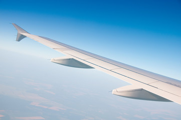 Obraz premium The wing of an airplane in the sky above the clouds.