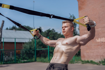 Male athlete close-up, trains nature city, summer training loops training, Feel your strength and...