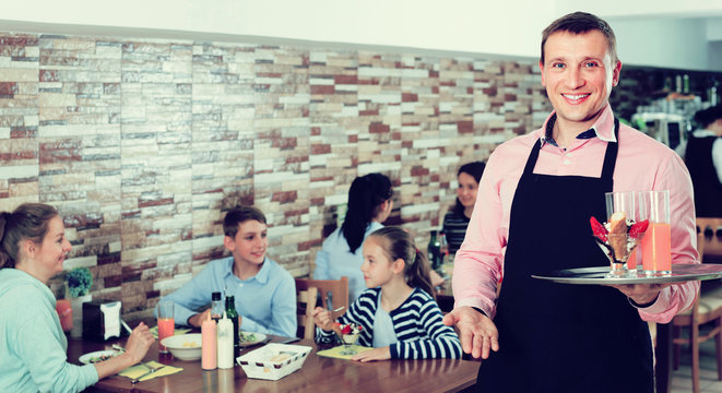 waiter warmly welcoming guests to cozy family cafe