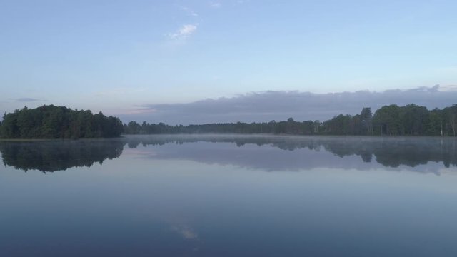 Aerial drone shot flying low over a misty and calm lake