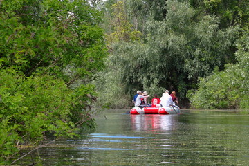 Team of people are having a water trip on inflatable catamaran on a wilderness Danube river reserve