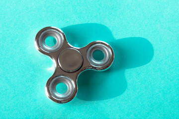 Fidget silver glossy finger spinner stress on blue. Copy space.