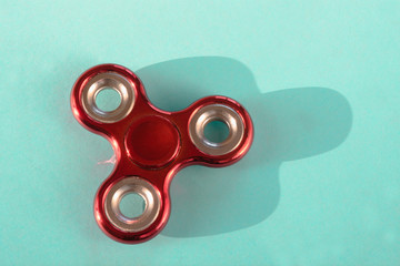 Fidget red glossy finger spinner stres on blue. Copy space.