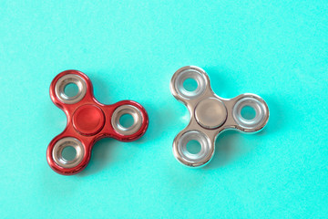 Fidget silver and red glossy finger spinner stress on blue. Copy space.