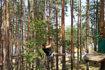 Little girl sliding on a zip line in adventure park