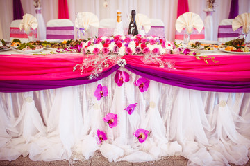 Dinner table for newlyweds decorated with orchids, pink and violet cloth