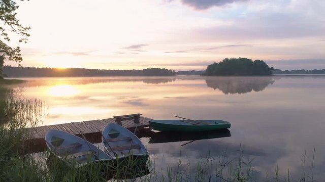 Aerial drone shot of boats next to a pier on a calm lake during sunrise