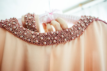Dress decorated with pearls hangs on the peg