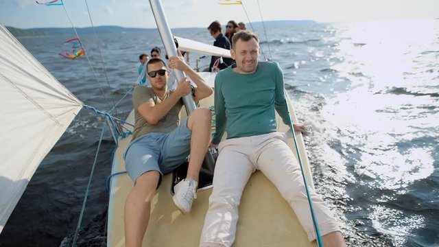 Men sitting on modern yacht posing and smiling at camera
