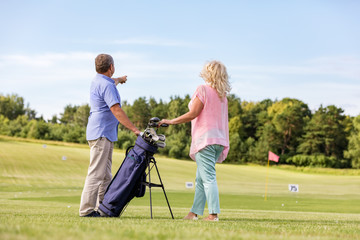 Active senior couple playing golf on a course.