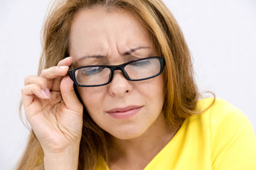 Fototapeta premium Closeup portrait, mature woman with black eye glasses trying to read book, having difficulties seeing text because vision problems. look down, trying to share the information below