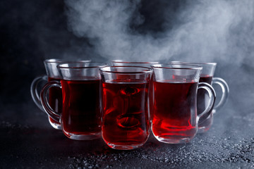 red cocktail with ice vapor. red cold tea with steam on a black background.