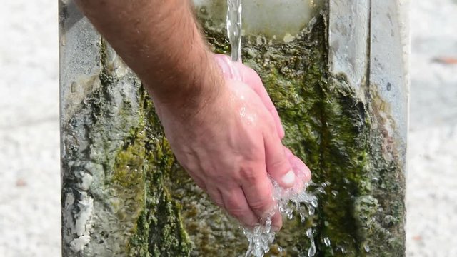 Wash the hands. Splashed water drops in a stone standpipe, in a park of Rome, Italy