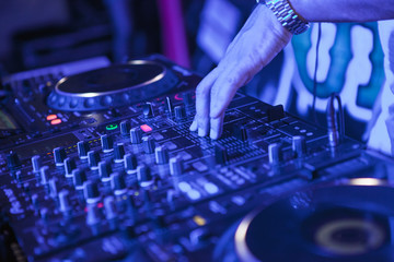 DJ playing music at mixer on colorful blurred background