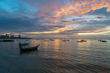 Many Thai fishing boat mooring in sea near Pattaya, Thailand at sunset.