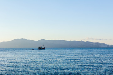 Fishing boat is crossing over calm sea