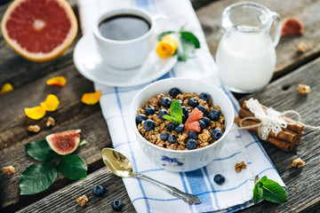 Muesli with blueberries on a napkin with a cup of coffee and a jar of milk