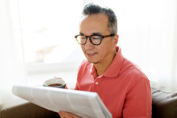 man drinking coffee and reading newspaper at home