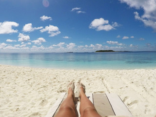 Fototapeta na wymiar View of womens legs, sunbathing on beautiful sandy beach 