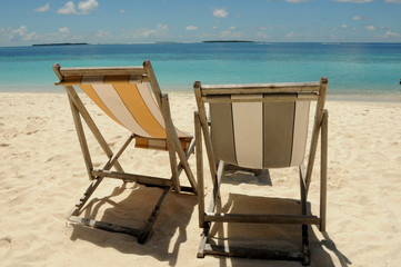Two Beach chairs looking out to the beautiful blue Indian Ocean, sitting on golden soft sand in the Maldives