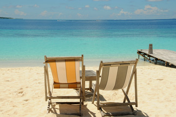 Two Beach chairs looking out to the beautiful blue Indian Ocean, sitting on golden soft sand in the Maldives