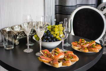 wedding glasses on a festive table with fruits and sandwiches with red fish, on a blurry background in the hotel room