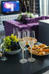 wedding glasses on a festive table with fruits and sandwiches with red fish, on a blurry background in the hotel room