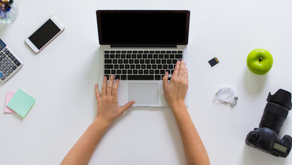 woman with camera working on laptop at table