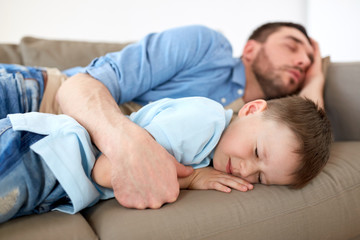 happy father and son sleeping on sofa at home