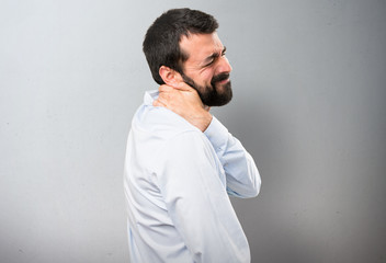 Handsome man with beard with neck pain on textured background