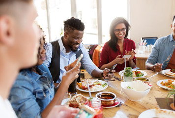 happy friends with smartphones at restaurant