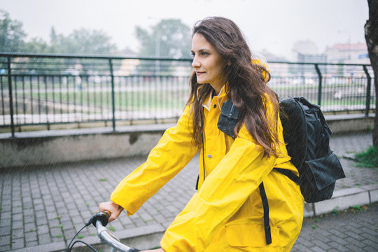Young woman cycling in the raincoat