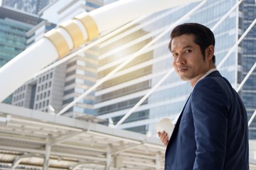 Confident businessman with coffee cup walking outdoors