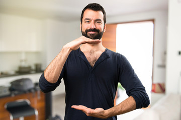 Fototapeta na wymiar Handsome man with beard holding something inside house