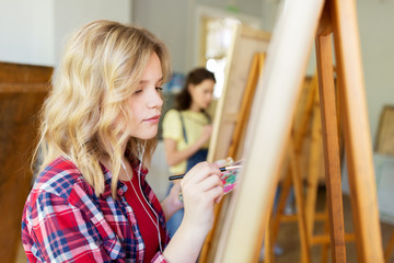 student girl with easel painting at art school © Syda Productions