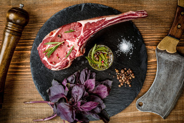 Dry aged raw tomahawk beef steak with ingredients for grilling