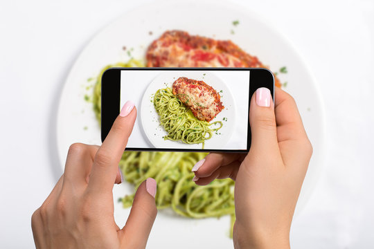 A young woman taking photo of food on smartphone, photographing meal with mobile camera