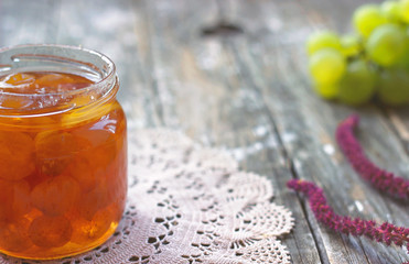 Slatko - preserved white grapes in glass jar, on wooden background; traditional serbian desert of white grapes or white cherries
