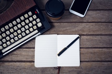 Overhead view of typewriter by disposable cup and book