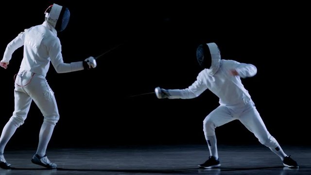 Two Professional Fencers Show Masterful Swordsmanship in their Foil Fight. Shot Isolated on Black Background  and in Slow Motion.