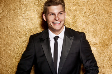 Handsome man on gold background, party. Luxury boy.