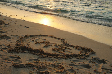 Heart shape Drawn in the sand with beautiful sunset
