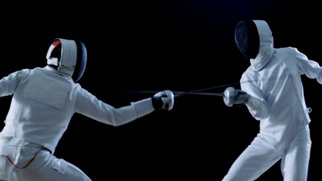 Two Professional Fencers Show Masterful Swordsmanship in their Foil Fight. They Dodge, Leap and Thrust and Lunge. Shot Isolated on Black Background  and in Slow Motion. 