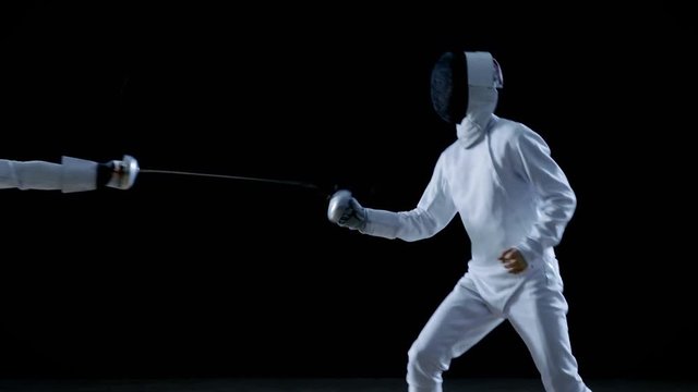 Two Professional Fencers Show Masterful Swordsmanship in their Foil Fight. They Leap and Thrust and Lunge. Shot Isolated on Black Background.  Shot on RED EPIC-W 8K Helium Cinema Camera.