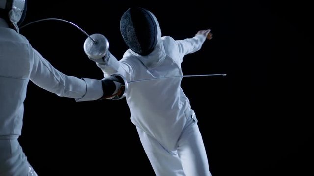 Two Professional Fencers Show Masterful Swordsmanship in their Foil Fight. They Attack, Defend, Leap and Thrust and Lunge. Shot Isolated on Black Background  and in Slow Motion.
